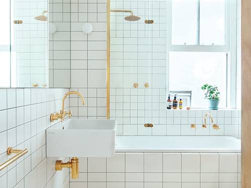 Pristine white bathroom with gold taps.